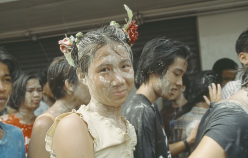 THAILAND, Bangkok, "Crowd covered in mud, young girl with flowers in hair,  celebrating the