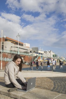 ENGLAND, East Sussex, Brighton, Woman using a laptop to surf the internet  in the free WiFi zone on