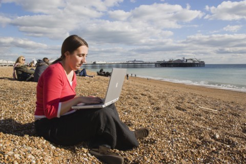 ENGLAND, East Sussex, Brighton, Woman using a laptop to surf the internet  in the free WiFi zone on