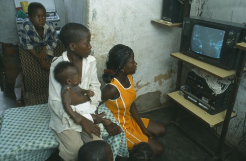 ANGOLA, Luanda, Bairro of Cacuoca.  Fifteen year old Maria Lydia at home watching television with