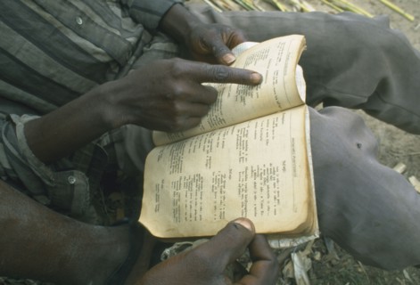 ANGOLA, Huambo, Kaala.  Displaced men living in disused factory practising reading skills with