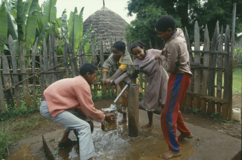 ETHIOPIA, Attat, Group of laughing children collecting water at hand pump.