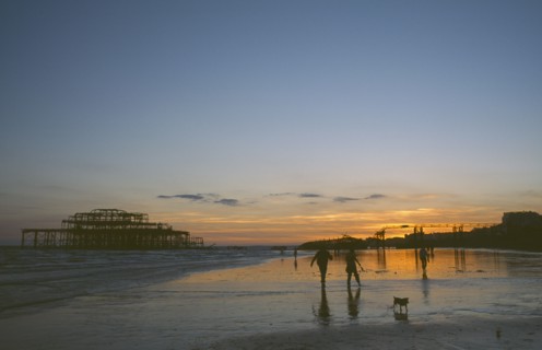 ENGLAND, East Sussex, Brighton, The ruined West Pier at sunset with low tide and a group of people