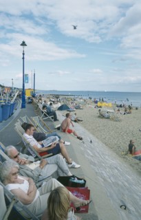 ENGLAND, Dorset, Bournemouth, People sat on deckchairs along seafront.