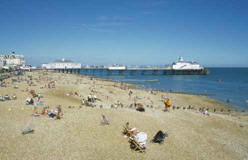 ENGLAND, East Sussex, Eastbourne, View across busy shingle beach towards pier.