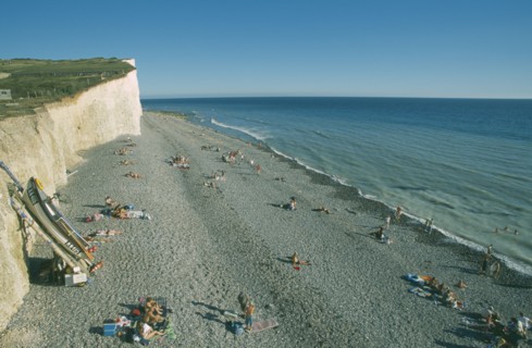 ENGLAND, East Sussex, Birling Gap, View over occupied peeble beach with boat leaning against cliff
