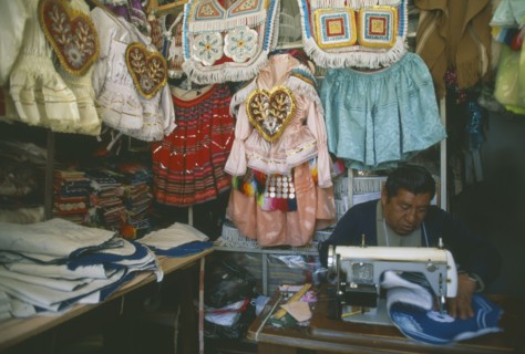 BOLIVIA, La Paz, Costume maker for Oruro Carnival. Man working on his sewing machine.