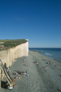 ENGLAND, East Sussex, Birling Gap, View across occupied peeble beach with boat leaning against a