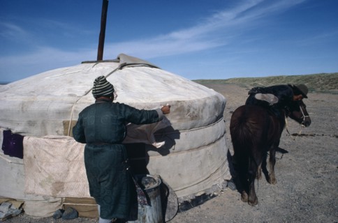 MONGOLIA, Gobi Desert , Herder mounting horse outside Yurt in the southern Gobi.