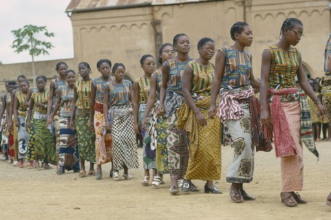 CONGO, Kimpese, Line of female dancers wearing colourful textiles at festival and watching crowd