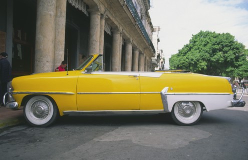 CUBA, Havana, "A classic yellow US 1950s car, parked on the Malecon."