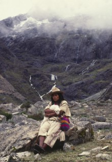 COLOMBIA, Santa Marta, Sierra Nevada , "Ica Indian with lamb sat on a rock, surrounded by mountains