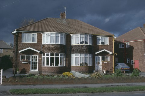 ENGLAND, Yorkshire, Leeds, Semi detached housing with a single car parked in the driveway.
