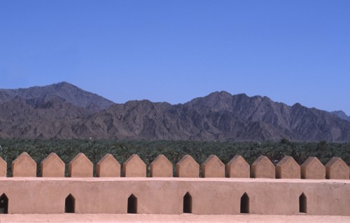 OMAN, Landscape, "Wall of a traditional fort, with Oasis and mountains behind."