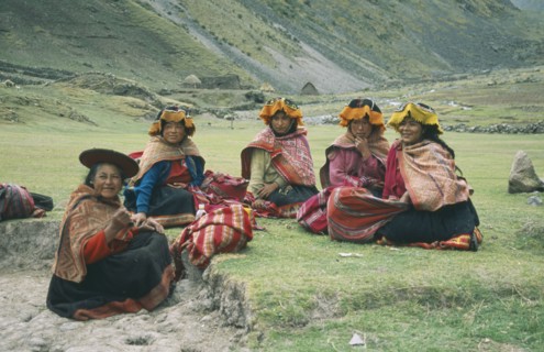 PERU, Cusco, Cancha Cancha, "Local Quechuan women sat on grass, wearing traditional dress."