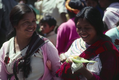GUATEMALA, Chichicastenango, "Two indegenous women smiling, one holding sweetcorn."
