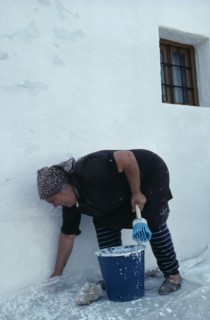 SPAIN, Andalucia, Andalucian village woman white washing the exterior wall of her home.