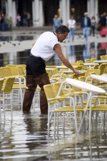 ITALY, Veneto, Venice, Aqua Alta High Water flooding in St Marks Square with waiter wearing waders
