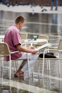 ITALY, Veneto, Venice, Aqua Alta High Water flooding in St Marks Square with an artist painting a