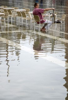ITALY, Veneto, Venice, Aqua Alta High Water flooding in St Marks Square with an artist painting a