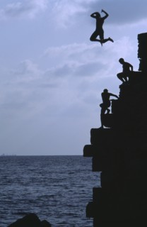 ISRAEL, Acre, Arab boys climbing the old harbour walls to jump into the sea with a boy leaping into