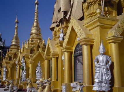 MYANMAR, Yangon, Shwedagon Paya.  Golden shrines and statues in temple complex.