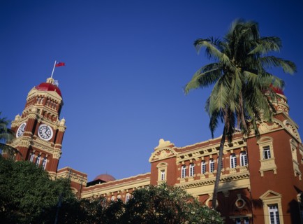 MYANMAR, Yangon, Part view of exterior of historic post office building and clock tower with palm