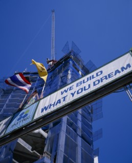 THAILAND, Bangkok, Looking up at sign ‘We Build What You Dream’ with high rise building under