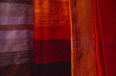 MOROCCO, Essaouira, Detail of red  orange and pale purple / blue woven textiles.