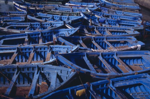 MOROCCO, Essaouira, Blue and green fishing boats moored closely together.
