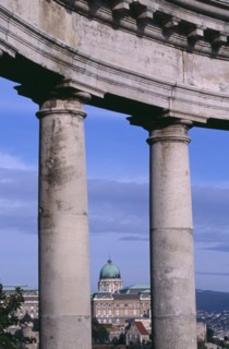 HUNGARY, Budapest, Copper dome of the Royal Palace rooftop and cityscape seen between stone pillars
