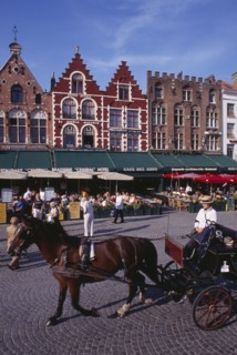 BELGIUM, West Flanders, Bruges, The Markt (Market Place).  Horse drawn carriage passing line of