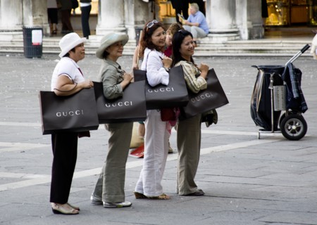 ITALY, Veneto, Venice, Asian tourists in St Marks Square posing for photographs whilst shouldering
