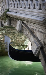 ITALY, Veneto, Venice, The Ferro at the bow of a gondola passing under a footbridge over a canal