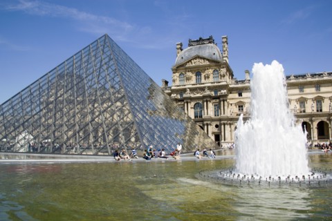 FRANCE, Ile de France, Paris, Tourists sitting beside the fountain pools in the Cour Napoleon at