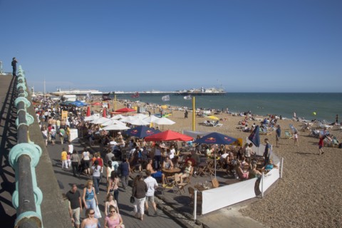 ENGLAND, East Sussex, Brighton, People sat at tables outside seafront bars and cafes.