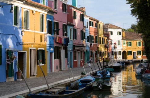 ITALY, Veneto, Venice, Colourful houses beside a canal on the lagoon island of Burano with boats
