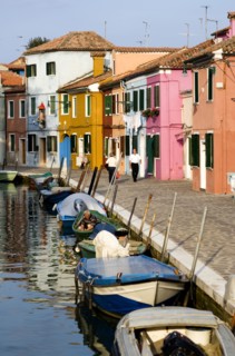 ITALY, Veneto, Venice, Colourful houses beside a canal on the lagoon island of Burano with people
