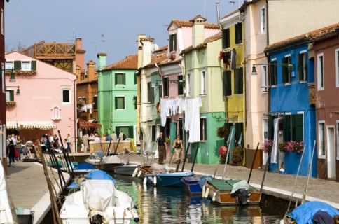ITALY, Veneto, Venice, Colourful houses beside a canal on the lagoon island of Burano with people
