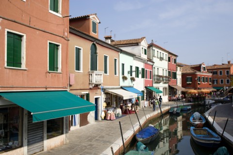 ITALY, Veneto, Venice, Colourful houses beside a canal on the lagoon island of Burano with boats