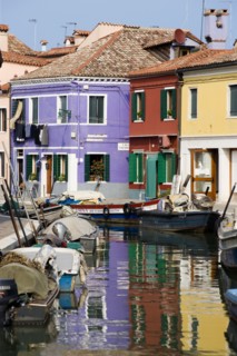 ITALY, Veneto, Venice, Colourful houses beside a canal on the lagoon island of Burano with boats