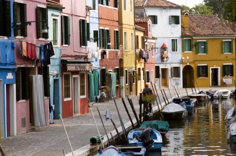 ITALY, Veneto, Venice, Colourful houses beside a canal on the lagoon island of Burano with boats