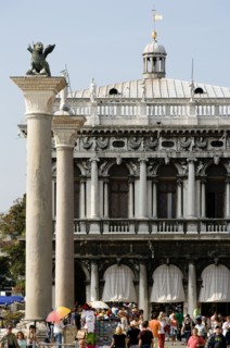 ITALY, Veneto, Venice, Tourists walk in the Piazetta below the winged Lion of Saint Mark on the