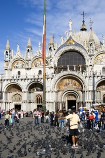 ITALY, Veneto, Venice, Tourists feeding pigeons in Piazza San Marco in front of St Marks Basilica