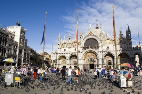 ITALY, Veneto, Venice, Tourists feeding pigeons in Piazza San Marco in front of St Marks Basilica