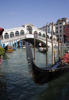 ITALY, Veneto, Venice, A gondola moored at the edge of the Grand Canal with another carrying