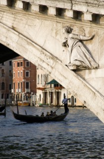 ITALY, Veneto, Venice, A gondola carrying tourists passes beneath the Rialto Bridge over the Grand