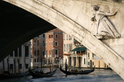 ITALY, Veneto, Venice, A gondola carrying tourists passes beneath the Rialto Bridge over the Grand