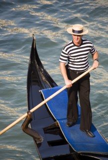 ITALY, Veneto, Venice, "A gondolier in traditional dress of beribboned straw hat, striped vest and
