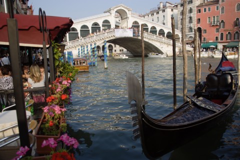 ITALY, Veneto, Venice, A gondola moored beside a restaurant on the Grand Canal with tourists dining